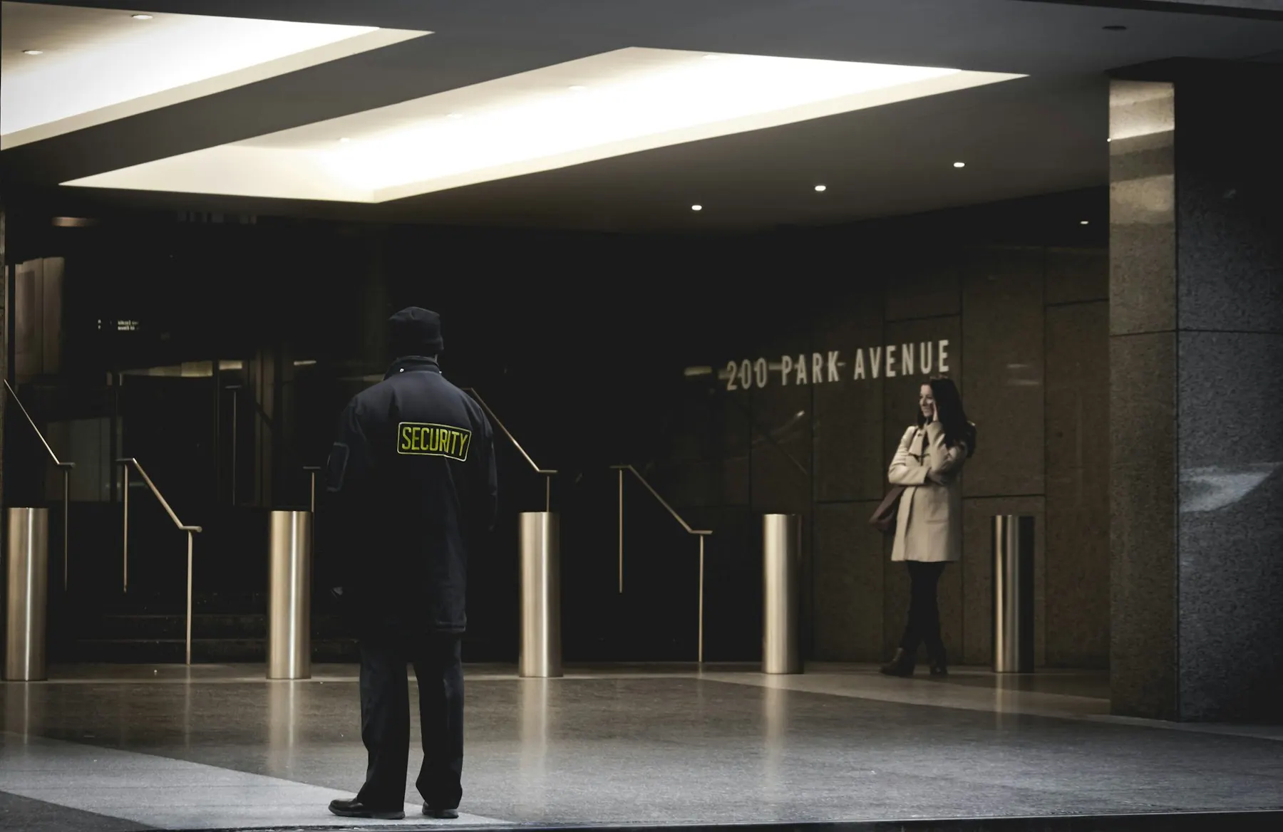 Agent de sécurité contrôlant l'accès d'un hall d'immeuble de nuit